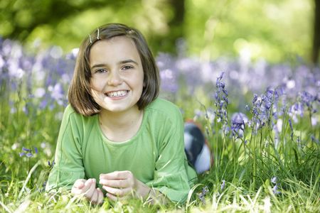 young girl lying in a wood full of bluebellsの写真素材
