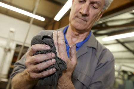 senior worker cleaning his hands with a clothの写真素材