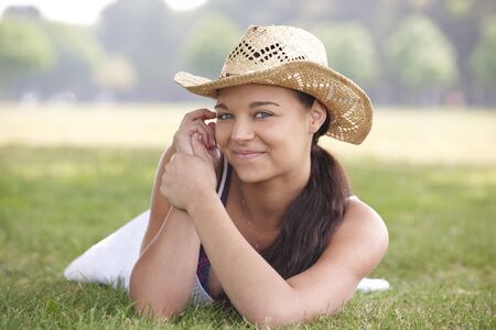 young attractive girl lying on grass wearing a summer hatの写真素材