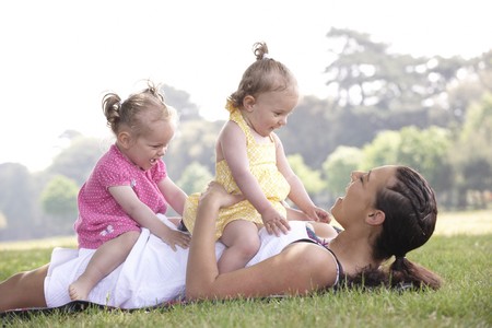 mother playing with daughters in the park in summerの写真素材