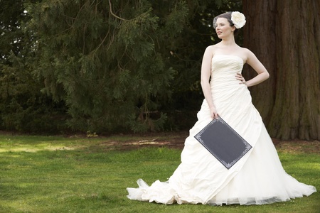 Pretty bride in wedding dress holding a blank board with space for copyの写真素材