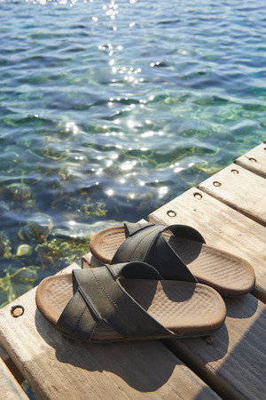 A pair of mens leather sandals on waterâs edge by seaの写真素材
