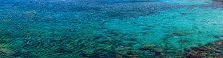 Panorama of clear sea water in Mediterranean showing coral and rocks just under the surfaceの写真素材
