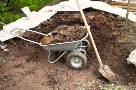 Heap of manure, soil, in a wheelbarrow and shovelの写真素材