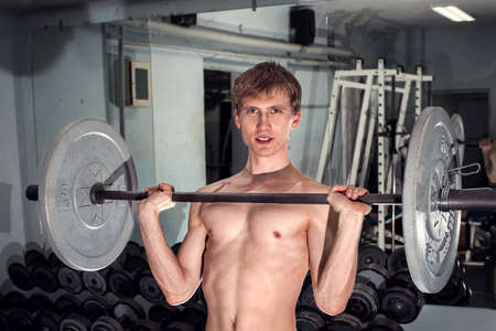 Young man in the old gym. Barbell exercise Standingの写真素材