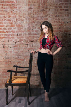 Girl in plaid shirt on brick wall background. Chairの写真素材