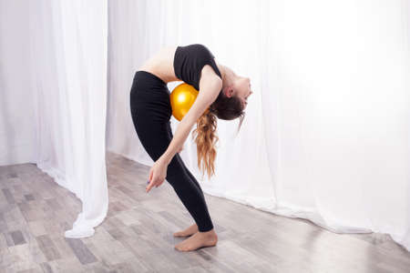 Gymnast with a ball exercising. Flexibility in the backの写真素材