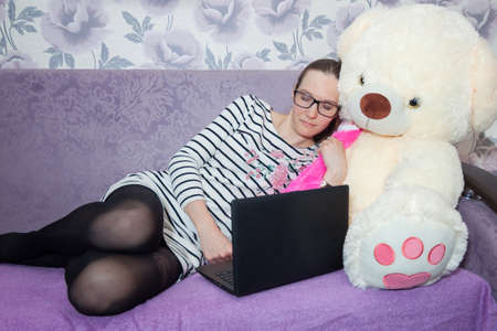 Cute girl tired of work, sleeping at home on the couch with a teddy bearの写真素材