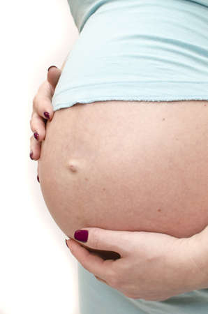 A young pregnant woman touching her hands to the bellyの写真素材