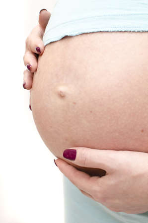 A young pregnant woman touching her hands to the bellyの写真素材