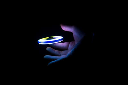 Play Fidget spinner spinning and Hand on dark background With Ligthtの写真素材
