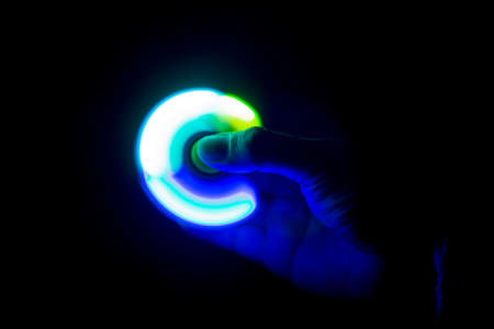 Play Fidget spinner spinning and Hand on dark background With Ligthtの写真素材