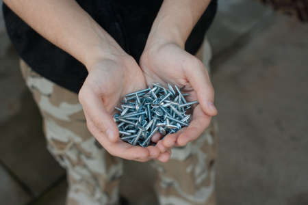 Young man holding screws outdoorsの写真素材