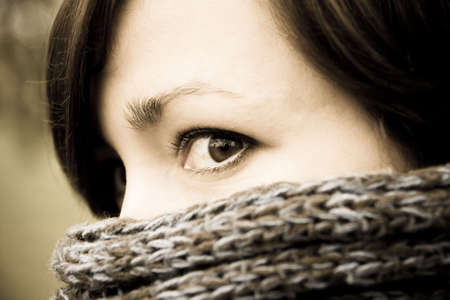 A mysterious portrait of a woman peeking from behind a scarfの写真素材