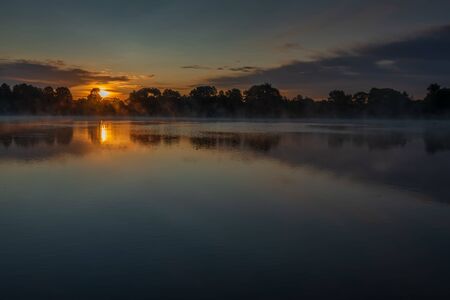 Bronze sunrise over the lake near the Joseph-Volotsky Monastery. Beautiful lake near the Joseph-Volotsky Monastery. The cloister is located in the village of Teryaevo, Volokolamsk municipal district of the Moscow region.の写真素材