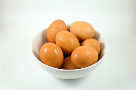 Chicken eggs in white bowl with water drop on egg surfaceの写真素材