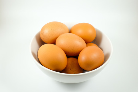 Chicken eggs in white bowl with water drop on egg surfaceの写真素材
