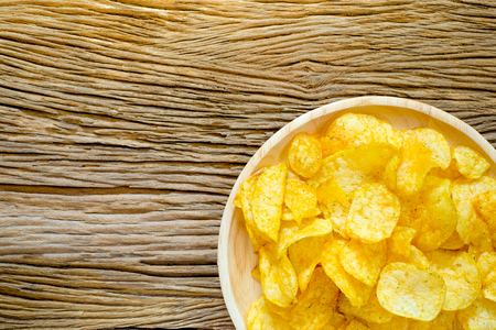 Crispy potato chips with seasoning in plate on sack with wooden background.の写真素材