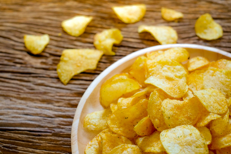 Crispy potato chips with seasoning in plate on sack with wooden background.(closed-up view)の写真素材