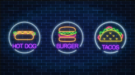 Set of three neon glowing signs of burger, hot dog and tacos in circle frames on a dark brick wall background. Fastfood light billboard symbol. Cafe menu item. Vector illustration.のイラスト素材