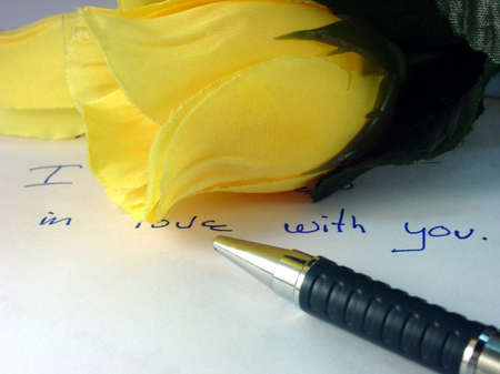 Photo showing  pen layin in front of yellow rose in nice  valentine setting
