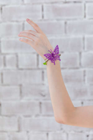 Arm girls with butterfly against a backdrop of brick wallの写真素材