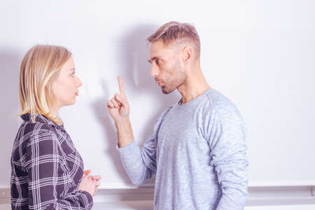 Young man with menacing gesture towards his girlfriend