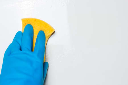 Prevent coronavirus concept. Close up view of hand with rubber glove cleaning white table. Copy space.の写真素材