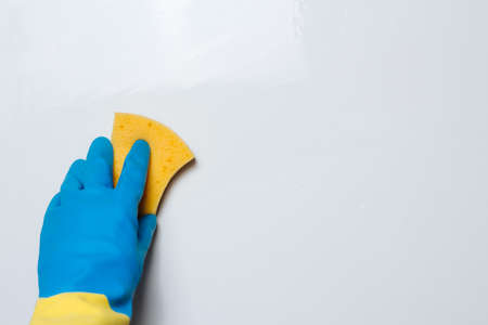Disinfect to prevent expansion of the coronavirus concept. Close up view of hand wearing rubber glove cleaning white surfaceの写真素材