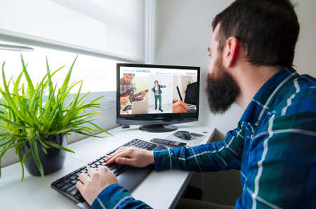 Education from home concept. Young man in front of computer with online courses website on the screenの写真素材