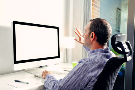 Young business man having video conference call via computer. Waving to camera on video call from...