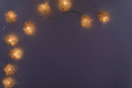 Christmas decoration frame with star shaped lights garland over purple background. New year concept