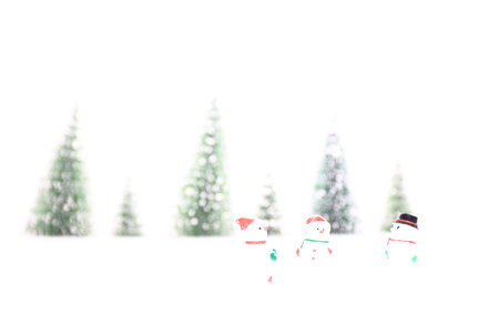 Winter and Christmas landscape composition.Three snowmen and row of pine trees in the background. Toy figures. Copy spaceの写真素材