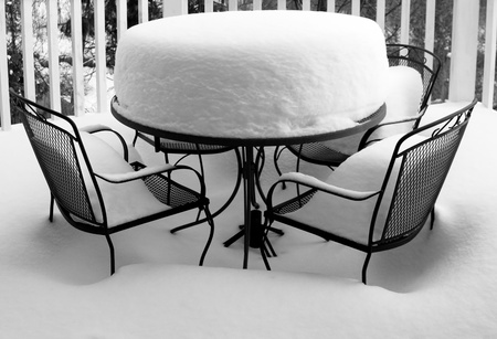 Garden in winter with wrought iron table and chairs covered in deep snow. Monochrome image and horizontal format.の写真素材