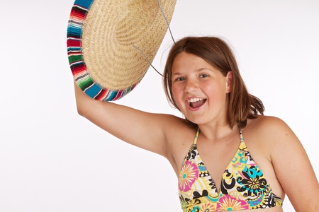 Cropped image of a laughing 12 year old girl happily waving her straw Mexican hat in the air  Isolated on white background with room for copy の写真素材
