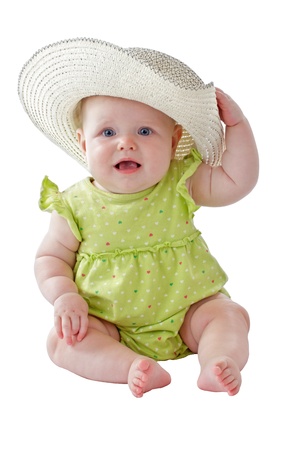 Happy 6 month old baby girl in green sun dress plays peekaboo with big straw hat. Isolated on white background, vertical, copy space.の写真素材