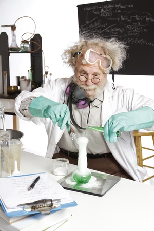 Amazed mad senior scientist in lab reacts to foaming green liquid overflowing beaker  Frizzy grey hair, round glasses, lab coat, aqua rubber gloves, blank blackboard, vertical, high key, copy space の写真素材