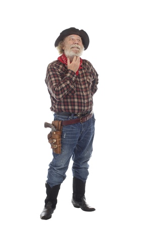 Classic old western style cowboy with felt hat, grey whiskers, stands scratching his whiskers. Isolated on white background, copy space, vertical.の写真素材