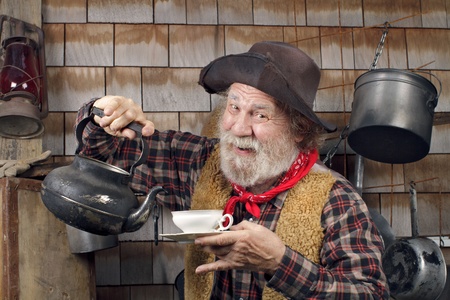 Classic old western style cowboy cook with felt hat, grey whiskers, red bandana. He is ready to pour...