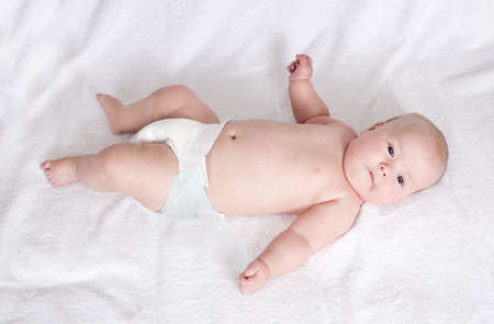 newborn baby lying on his back on a white bedspread