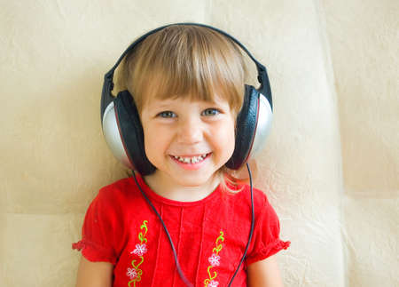 The cheerful girl in ear-phones listens to musicの写真素材