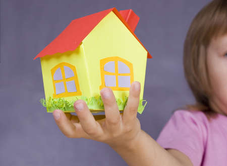Paper small house in a children's handの写真素材