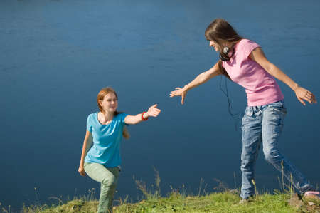 A girl helps her friend up the hillの写真素材