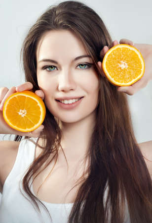 Portrait of a beautiful young girl with an orangeの写真素材