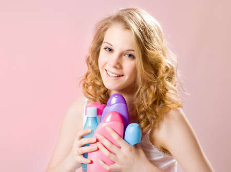 girl holds shampoos conditioners and shower gelの写真素材
