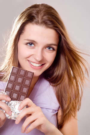 portrait smiling young woman eating a chocolate barの写真素材
