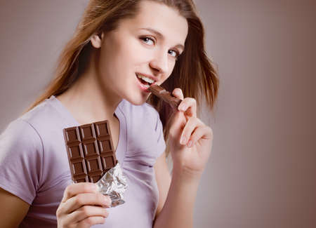 portrait smiling young woman eating a chocolate barの写真素材