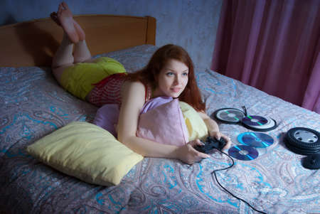 Young woman playing computer games on the bed at homeの写真素材
