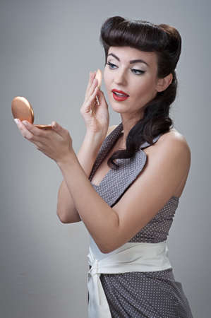 young beautiful caucasian girl powders her face, retro stylingの写真素材