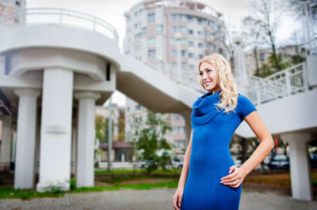 Beautiful girl in a blue dress on a city streetの写真素材